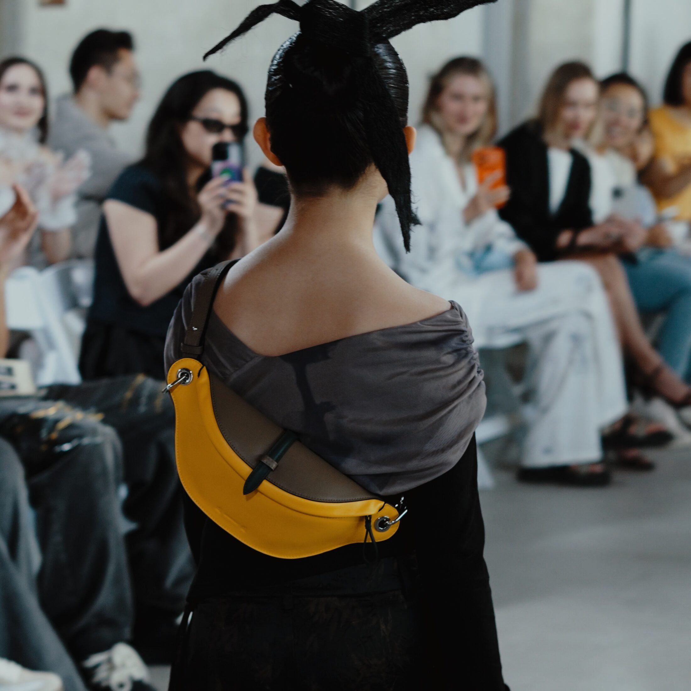 Yellow LAOGUI bag shown from behind with Fashion Art Toronto audience watching